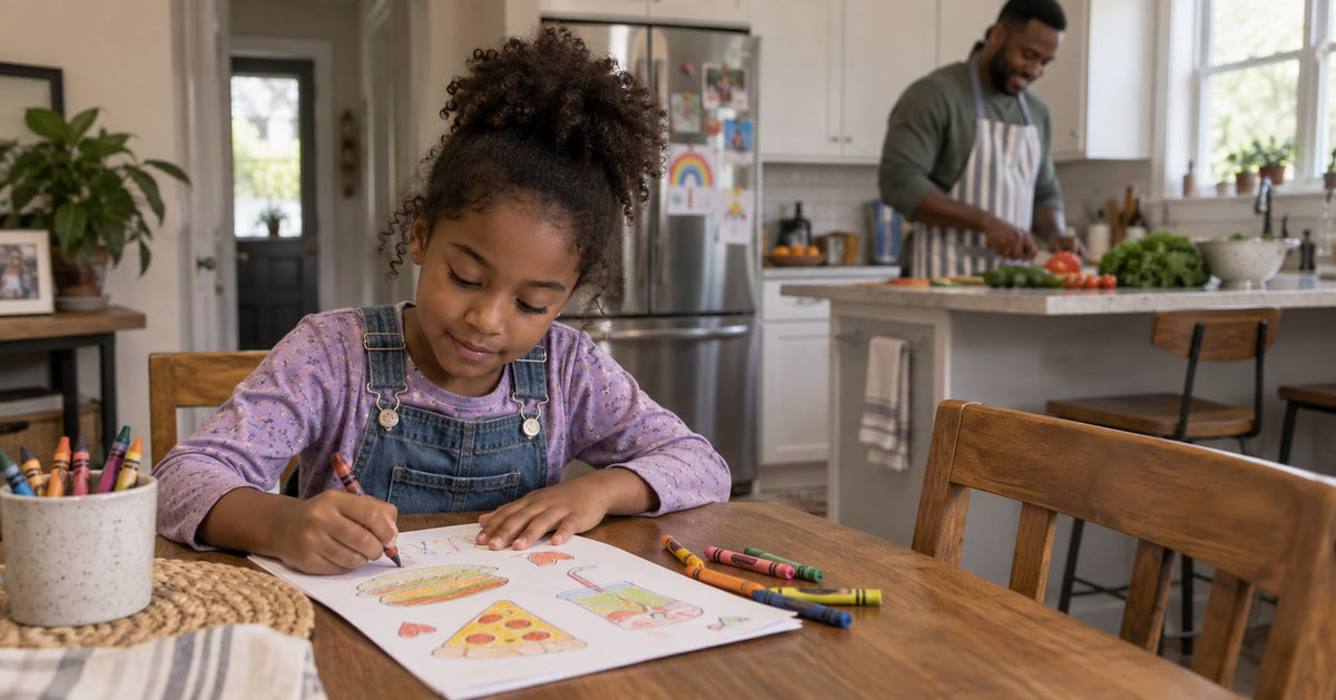 A child draws a pretend menu at a table while a parent prepares dinner nearby.